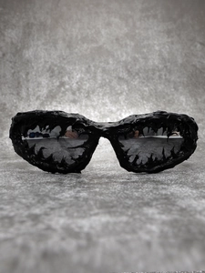 Detail of avant-garde black liquid-style sunglasses with glossy resin finish