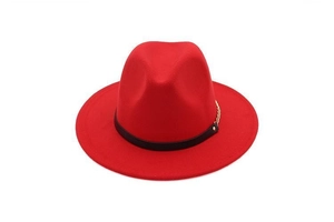 Detail of red fedora hat featuring black leather band and gold chain decoration