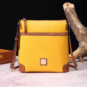 Detail shot of yellow pebbled leather crossbody bag with brown trim and gold hardware