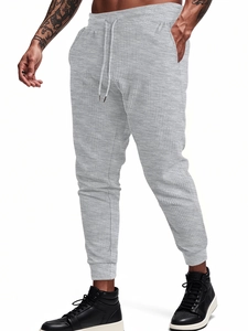 Detail of grey waffle knit joggers featuring drawstring waist and textured fabric surface