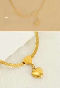 Close-up of golden stainless steel heart pendant on a stylish flat snake chain necklace