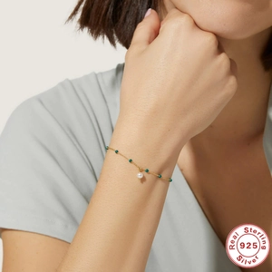 Detail of 925 sterling silver gold bracelet with green beads and pearl on wrist