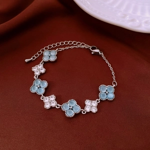 Detail of silver clover bracelet featuring light blue cat eye stones and white zircons