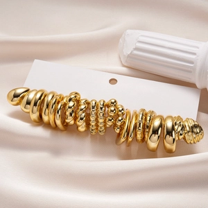 Détail d'un ensemble de vingt boucles d'oreilles dorées sur satin blanc soyeux