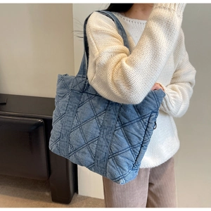 Vue détaillée du grand sac cabas matelassé en denim bleu porté avec une tenue décontractée