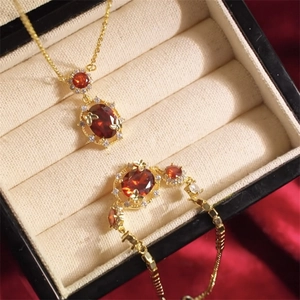 Detail of 18K gold plated jewelry set with red oval gemstones on luxury silk
