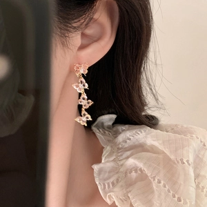 Elegant gold butterfly tassel earrings with pink zircons worn by a model in a close-up