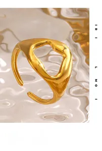 Detailed view of an irregular gold geometric hollow ring with polished finish on glass