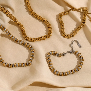 Detailed shot of 18K gold and silver twisted chain necklaces on beige silk fabric