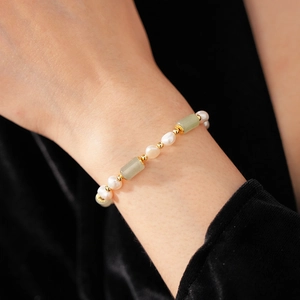 Detail of elegant pearl and green jade bamboo joint bracelet on a female wrist