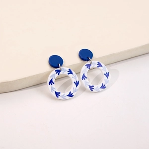 Detailed view of blue and white porcelain pattern acrylic earrings on a geometric stand