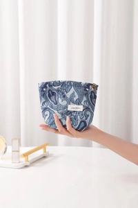 Close-up of blue paisley cosmetic bag with golden floral zipper and woven texture