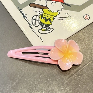 Detailed view of sweet pink cherry blossom hair clip with yellow resin center on a metal base