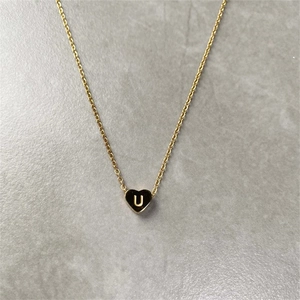 Detailed view of a golden stainless steel necklace with a tiny heart pendant engraved letter U