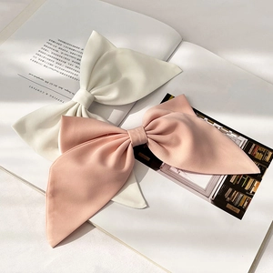 Pink and white fabric bow hair clips placed on an open book for a soft, elegant look