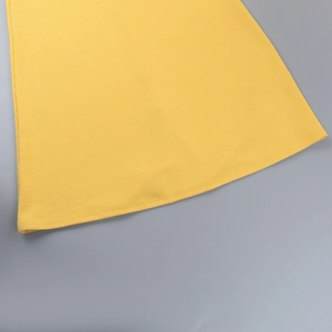 Détail de tricot jaune avec texture alvéolée et ourlet droit sur un fond gris mat