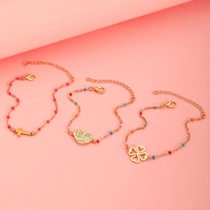 Detail of gold bracelets with cross, heart, and clover charms and colorful beads