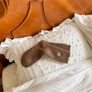 Close-up of brown wool knit socks with delicate flower embroidery on the cuff