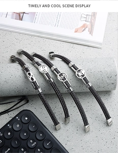 Close-up of four woven leather bracelets with infinity, skull, and music charms on a stone stand