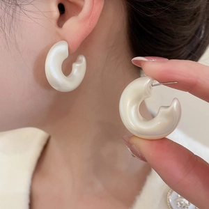 Detail of pearlescent white C-shaped hoop earrings showing texture and thickness