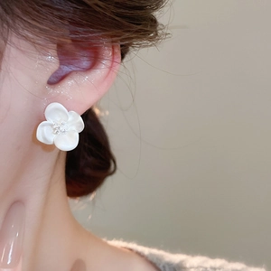 Close-up of elegant creamy white flower earring with micro-set crystals on female model