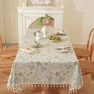 Close-up of beige linen tablecloth with floral pattern and decorative tassel fringe edges
