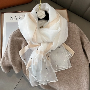 Detail of white silk scarf with golden borders, pearl beads on sheer fabric texture