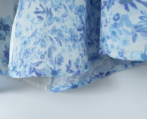 Close-up of fine lockstitch hem and porcelain blue floral print on chiffon dress