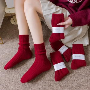 Thick red knitted winter socks for women featuring ribbed texture and slouchy style