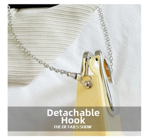 Detail showing the detachable silver metal hook and glossy leather texture of the bag