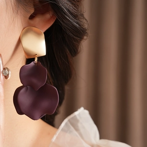 Close-up of golden irregular petal earrings with deep purple layered resin flowers on model