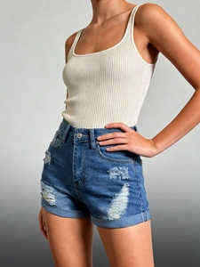 Detail of high-waisted distressed denim shorts with frayed edges and ripped accents