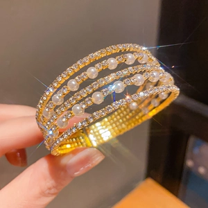 Elegant multi-layer gold bracelet featuring white pearls and sparkling rhinestones