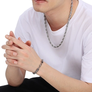 Gros plan d'un collier et d'un bracelet en acier inoxydable argenté sur un mannequin homme