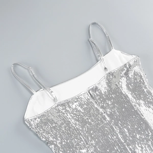 Detail of silver sequin dress showing thin straps and neckline texture on grey background