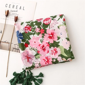Detail of floral printed cotton linen scarf featuring pink blossoms and dark green tassels