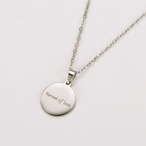 Detailed view of silver round pendant engraved with Harvest of Love on a fine chain