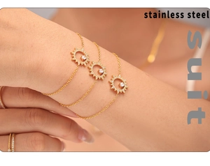 Gros plan sur un ensemble de trois bracelets dorés en acier inoxydable avec pendentifs soleil