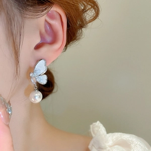 Détail d'une boucle d'oreille papillon en perle portée par un mannequin en gros plan