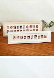 Detail of multi-aperture wooden photo frames in white and light wood finishes for portraits