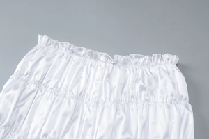 Close-up of white satin fabric texture featuring intricate pleated design and elastic structure