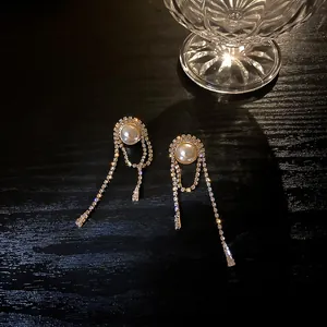Detailed close-up of long tassel earrings with sparkling rhinestones and large pearls