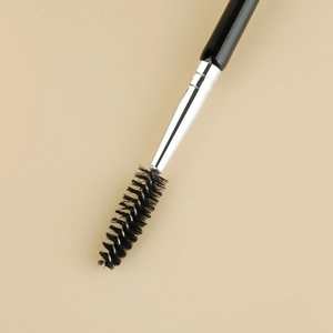 Macro shot of double-ended eyeshadow and spoolie brush with a black wooden handle