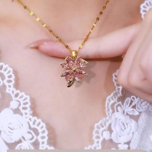 Detailed close-up of pink faceted clover necklace with a golden chain on a female neck