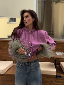 Purple knit cardigan with feather cuffs and gold buttons paired with blue jeans
