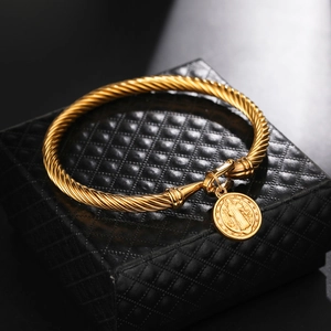Close-up of golden stainless steel twisted rope bracelet with religious pendant