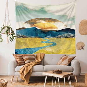 Artistic tapestry with golden sun and blue mountain landscape hanging above a sofa