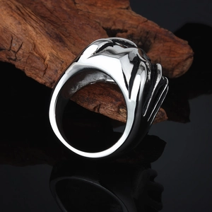Rugged silver stainless steel skull claw ring for men displayed on textured natural wood bark