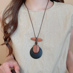 Detail of vintage wooden pendant necklace with round and oval shells on beige linen