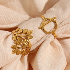 Detailed view of 18K gold leaf and geometric rings on pink silk fabric background